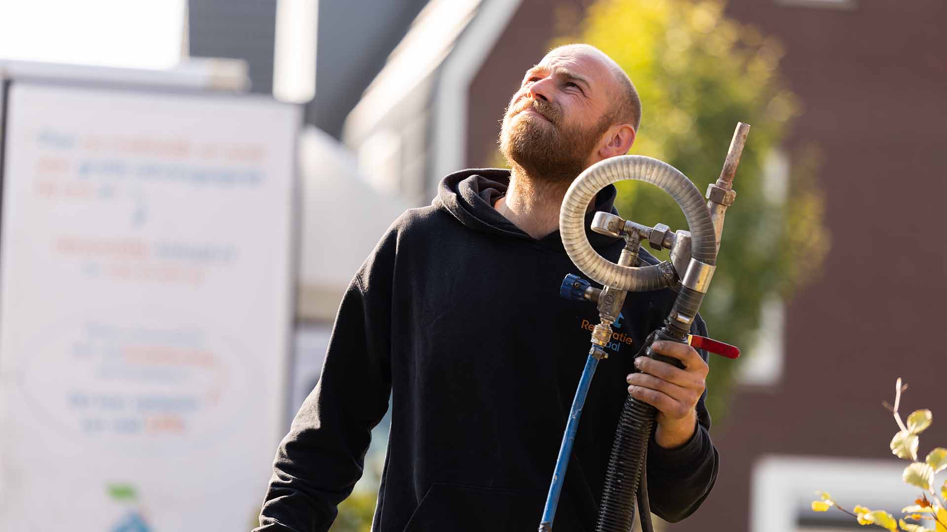 Medewerker van Renovatie Totaal met de slang van een inblaasmachine
