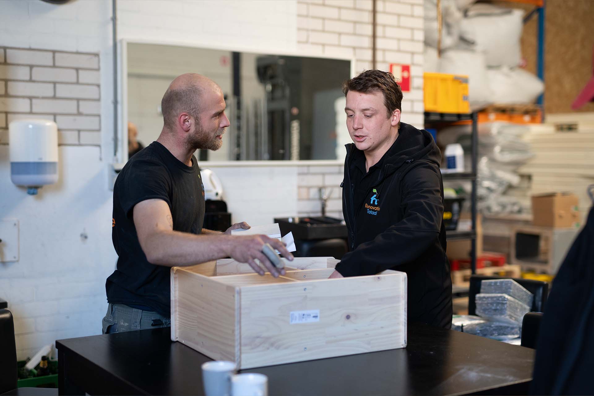 Twee medewerkers van Renovatie Totaal overleggen in de werkplaats